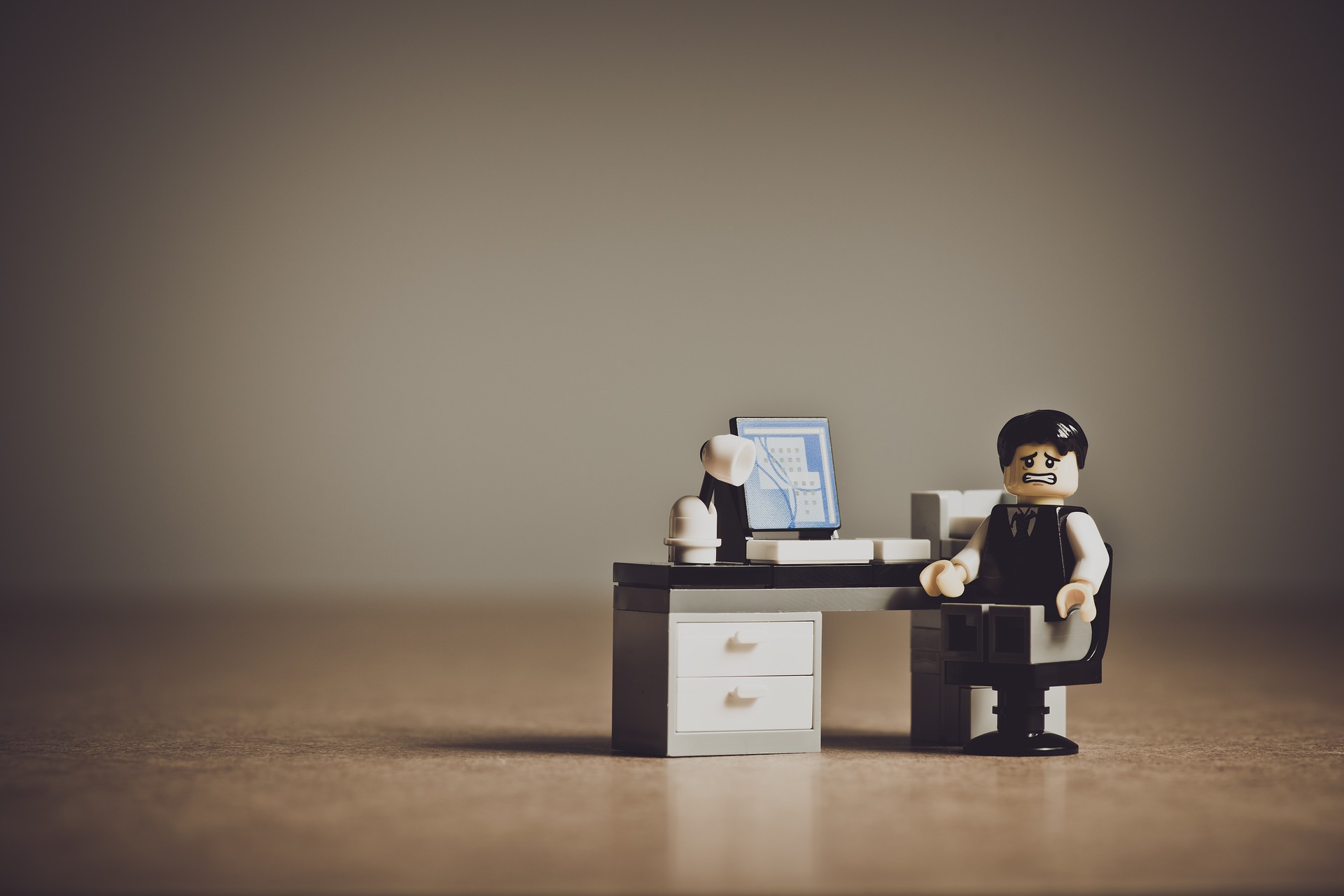 een poppetje zit angstig kijkend voor een bureau