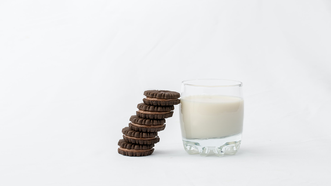 een glas melk met een stapeltje koekjes ernaast