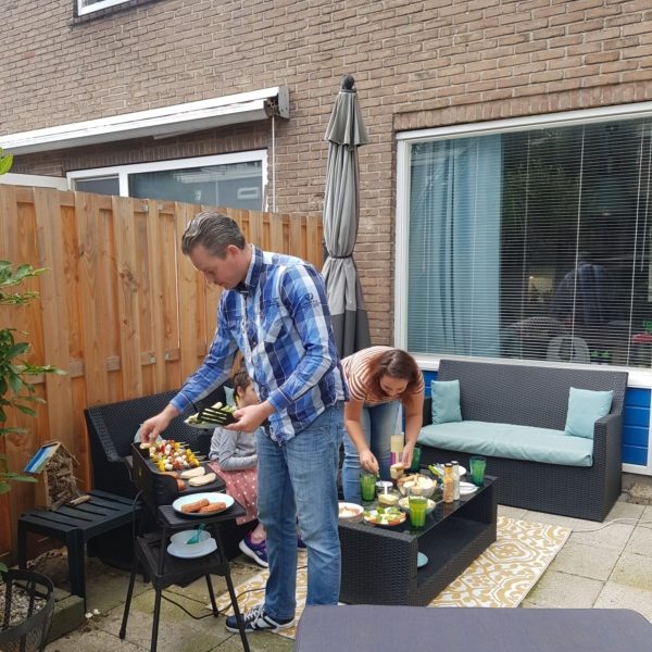 Annabel en Tim in hun tuin, bezig met de BBQ