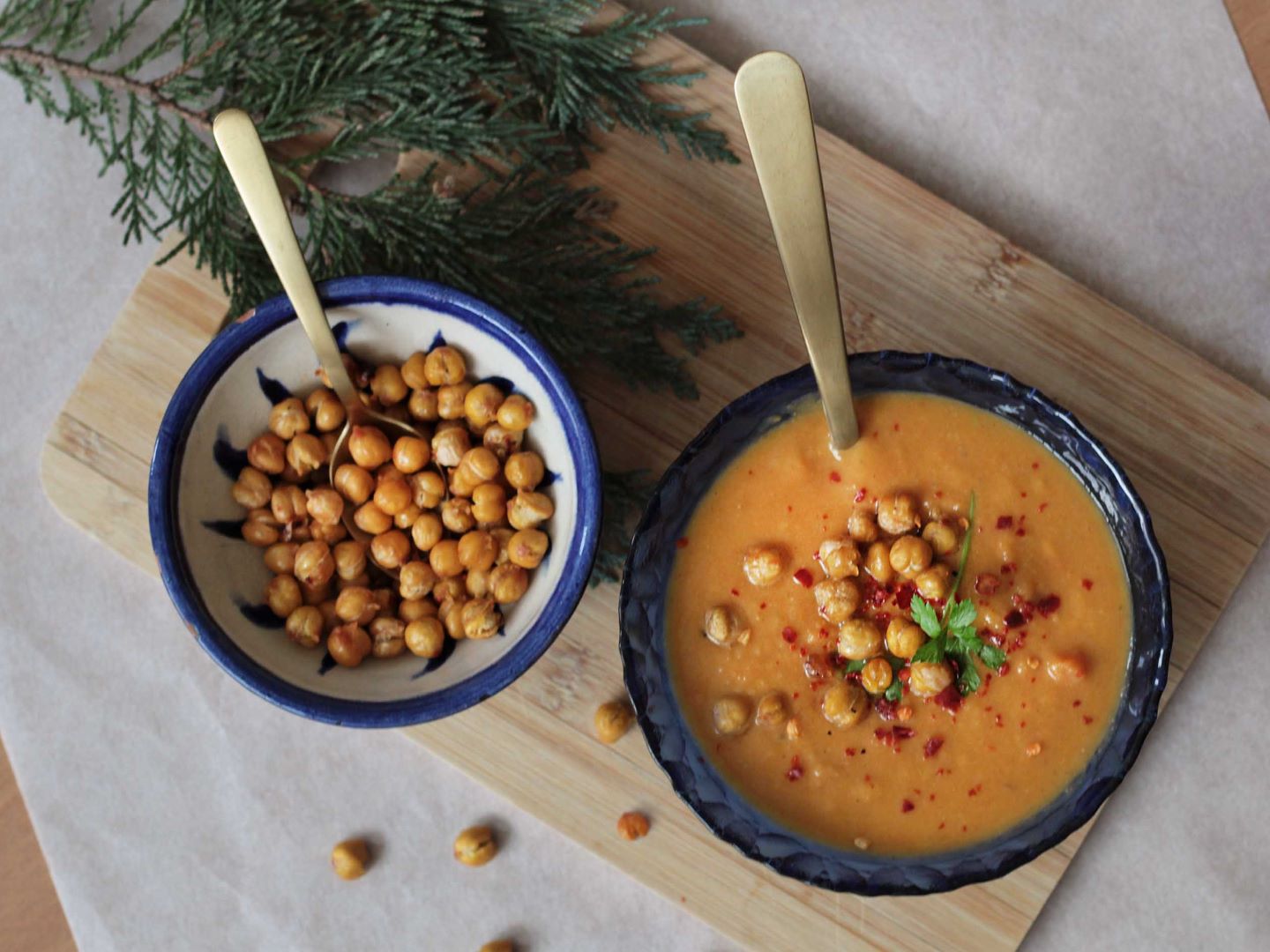 Een kom romige zoete aardappelsoep met daarnaast een kom met geroosterde kikkererwten