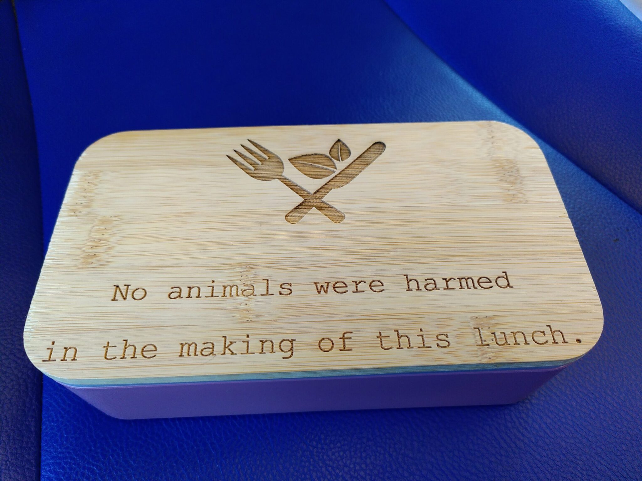 Pink lunch box with wooden lid with engraved the text: "No animals were harmed in the making of this lunch."