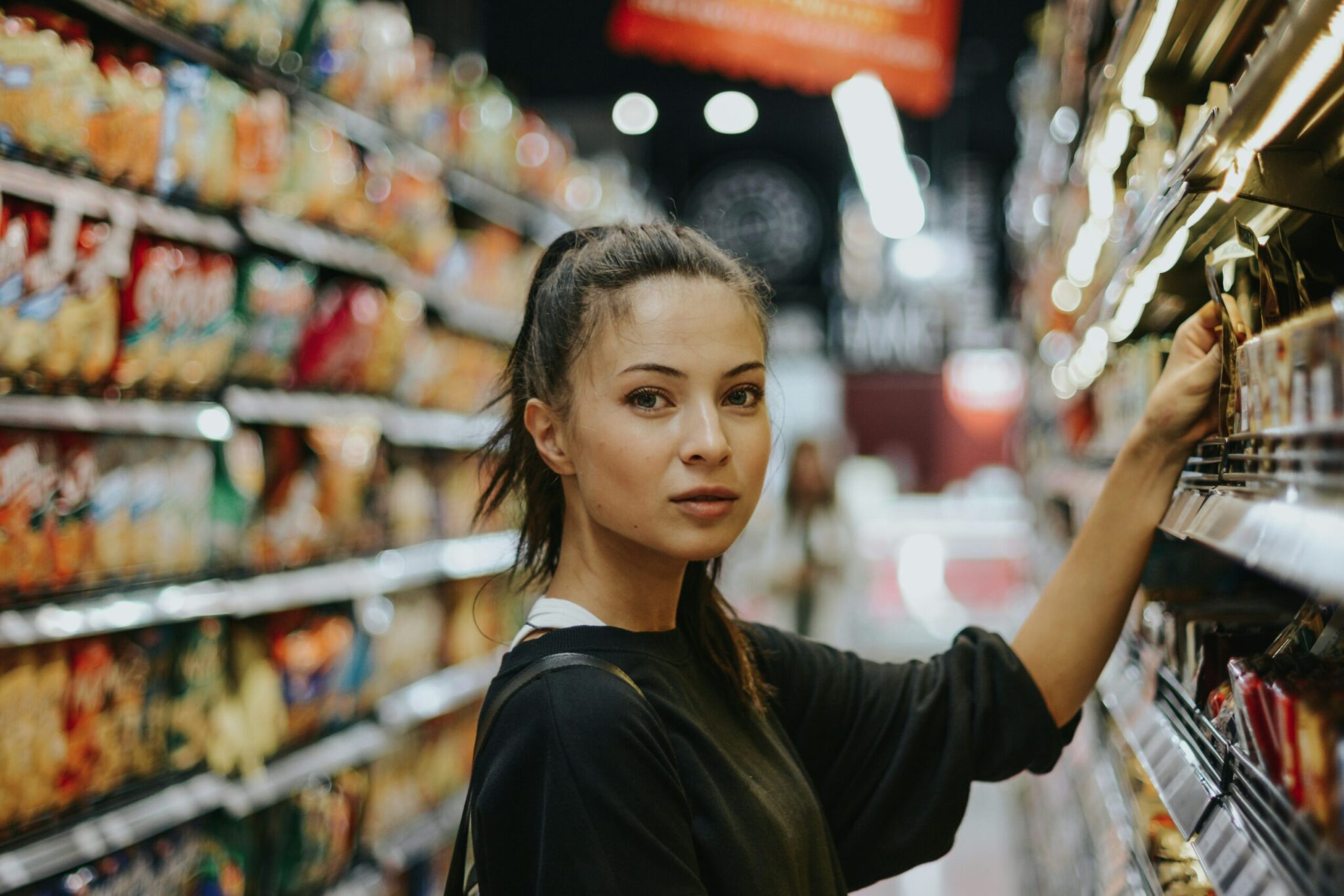 Iemand pakt iets uit een schap in een supermarkt.