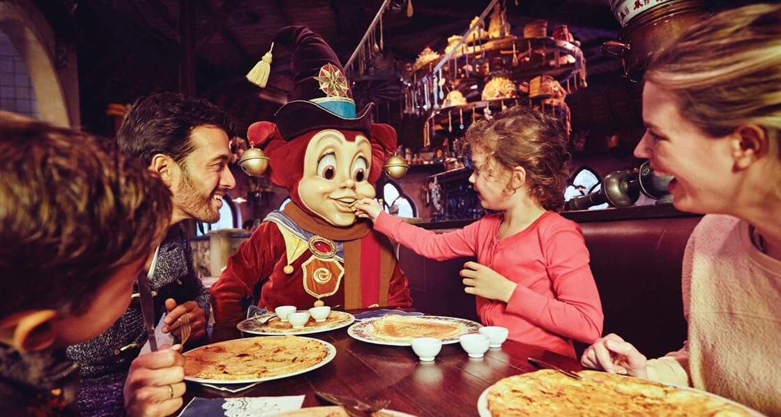 Uit eten in een pannenkoekenrestaurant in de Efteling. Mascotte Pardoes zit ook aan tafel en wordt door een kind gevoerd.