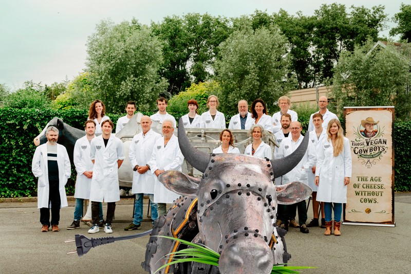 Groepsfoto met mensen in witte laboratoriumjassen, met op de voorgrond een stalen koe