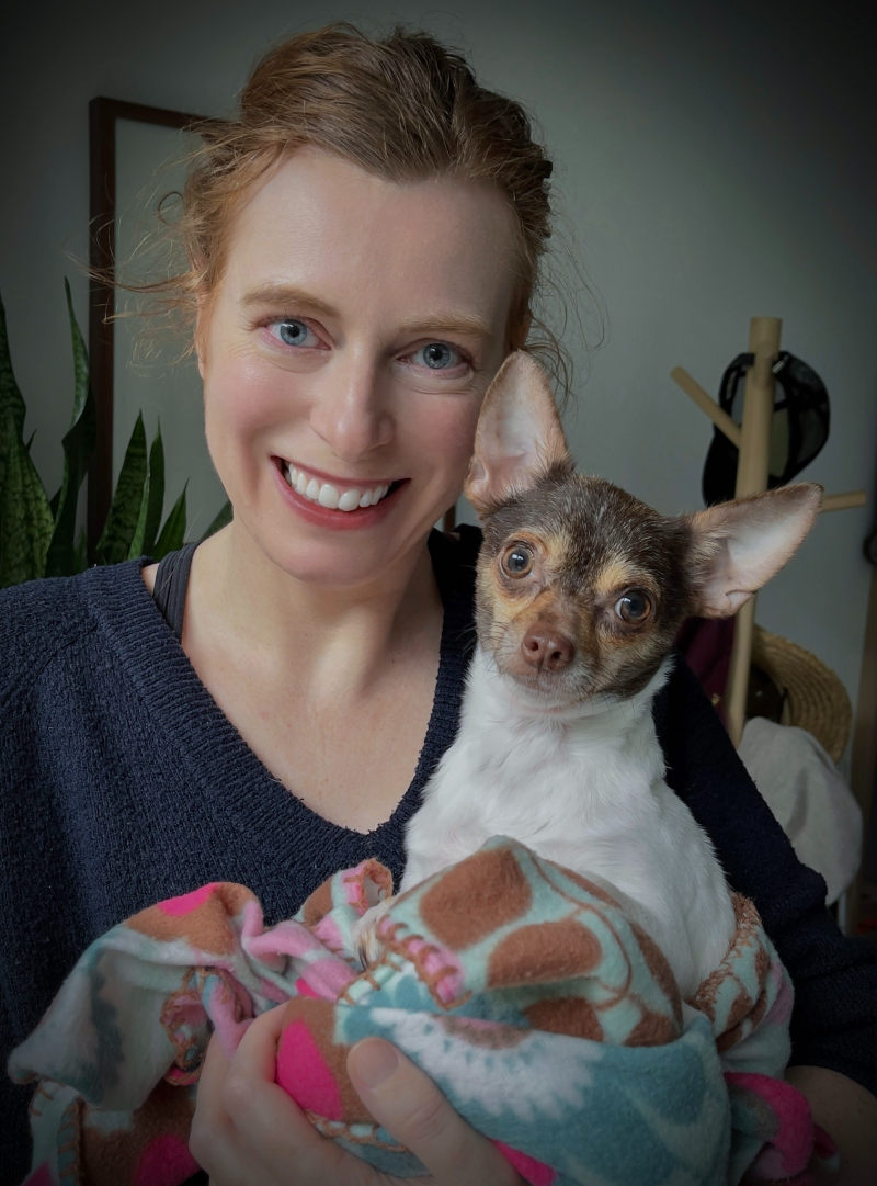 Foto van Marijke Hoebee die een hondje in haar armen houdt.