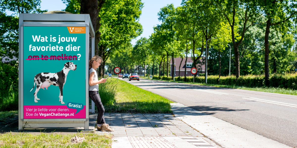 Mock-up van de NVV-campagne op een bushokje, met het beeld van een hond met grote uiers.