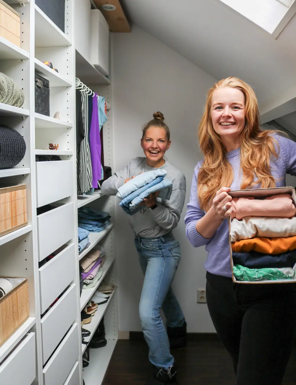 twee-veganisten-in-kledingkast Foto van Saskia van Amerongen en vriendin die met opgevouwen kleding voor een kast staan.