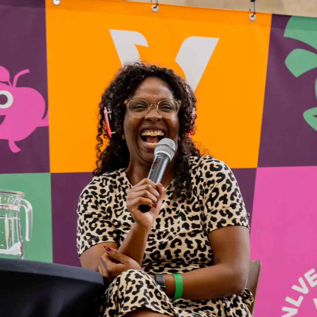 NLVegan Fair 2026- Trai- marijke hoebee Foto van een lachende Trai met een microfoon in haar hand.