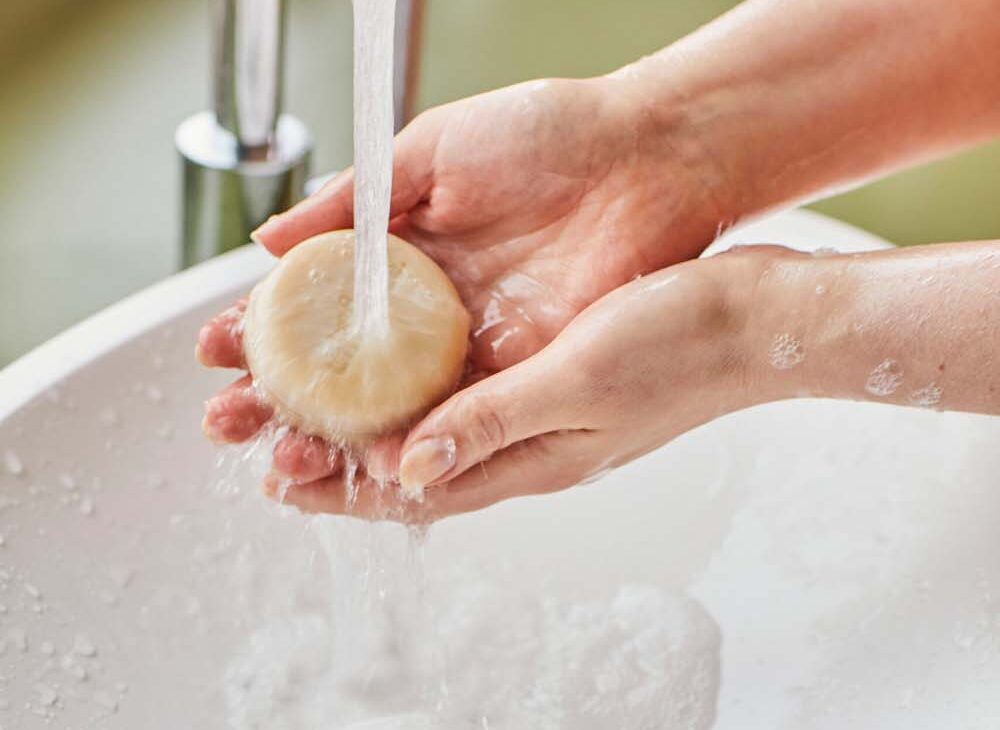Zeepje van Unwaste en iemand die het onder de kraan houdt waarvan je alleen de handen ziet